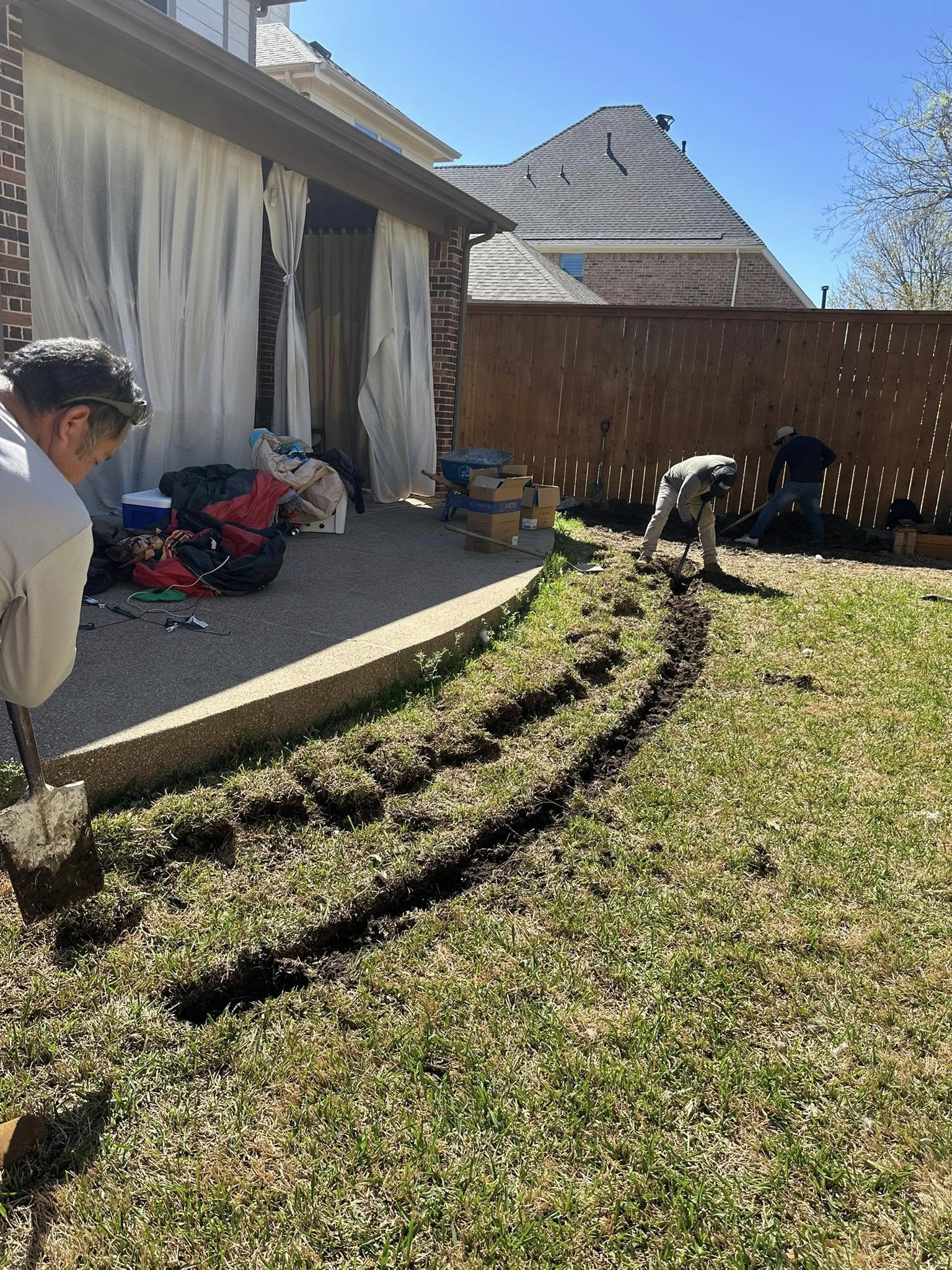 Curved drainage trench installation near patio