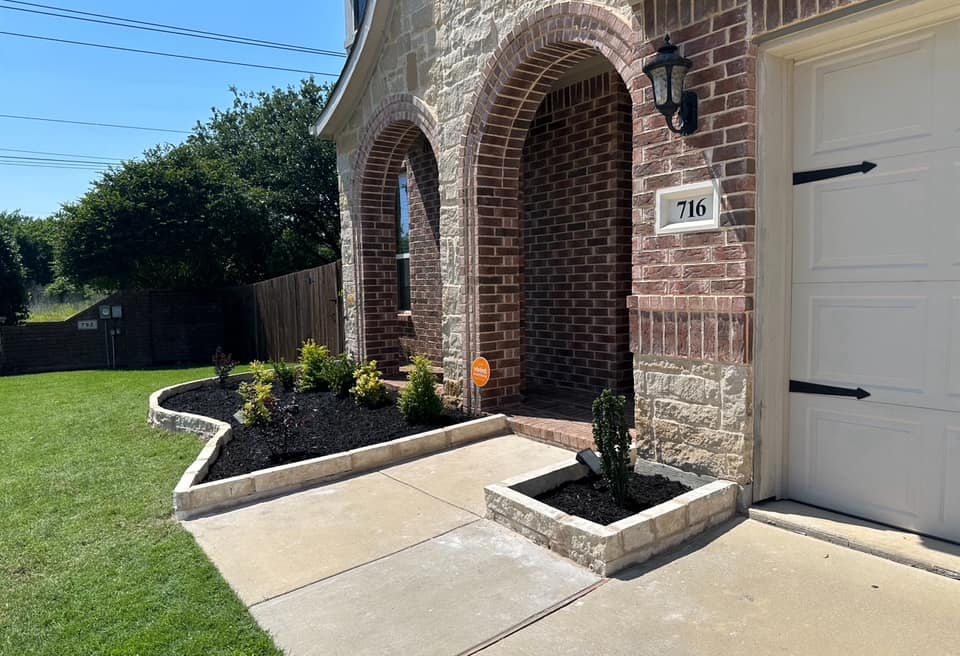 Front yard landscape beds with stone border and plants