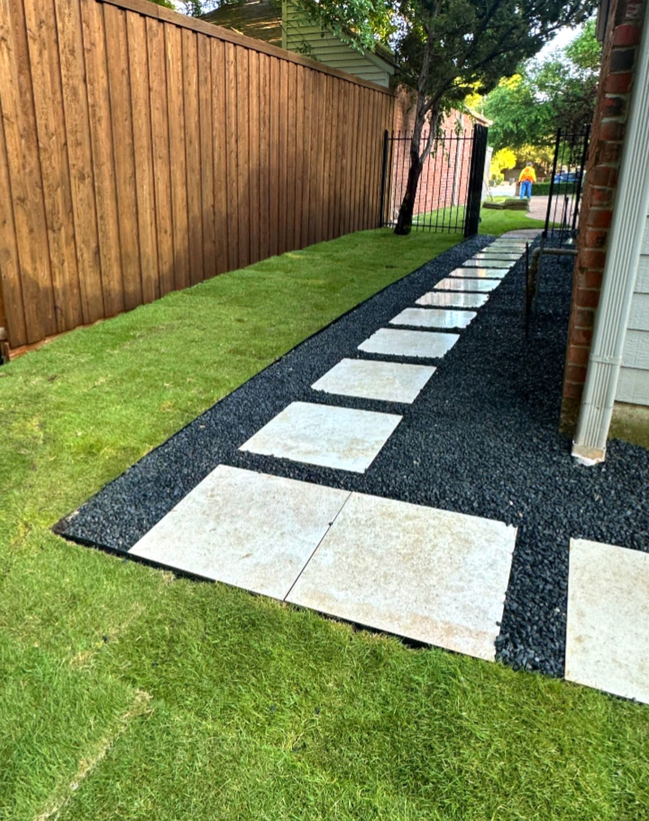 Modern stepping stone walkway with black gravel and sod